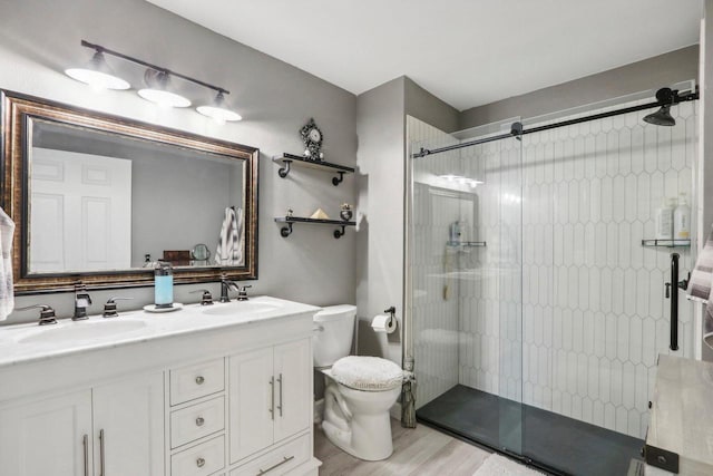 bathroom featuring double vanity, toilet, a stall shower, and a sink