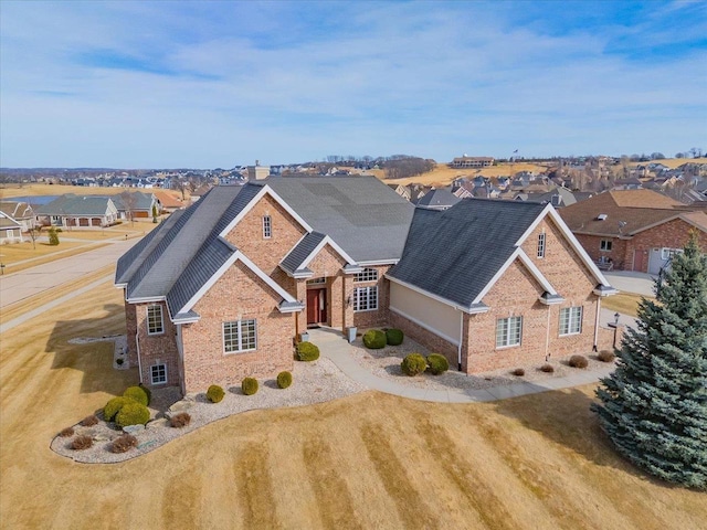 traditional home featuring brick siding, a residential view, and a shingled roof