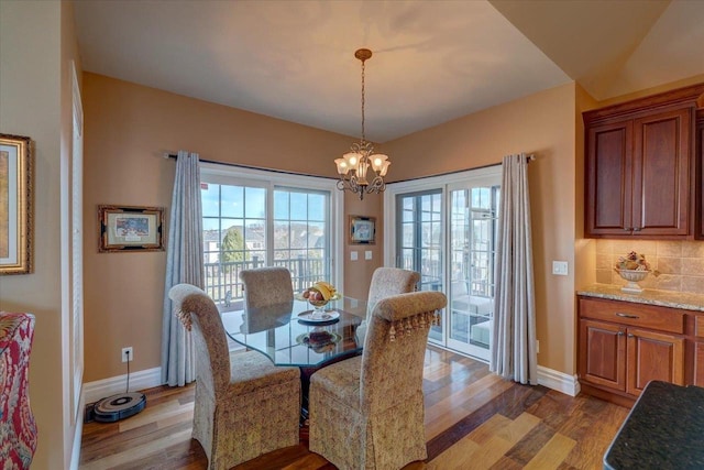 dining room with wood finished floors, baseboards, and a chandelier