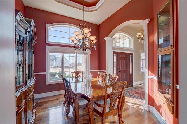 dining room with arched walkways, an inviting chandelier, and wood finished floors