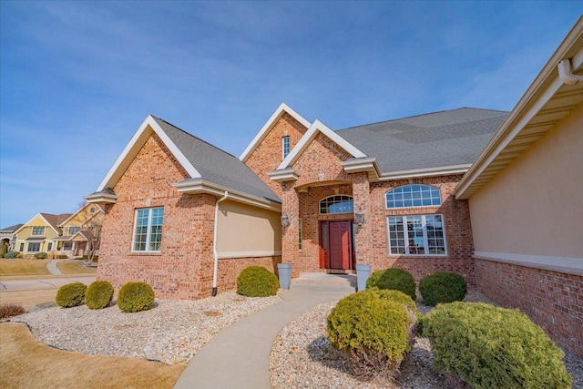 view of front of house featuring brick siding and roof with shingles