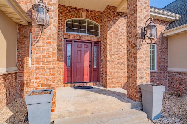 entrance to property with brick siding and a shingled roof