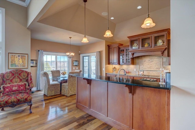 kitchen with pendant lighting, dark stone countertops, backsplash, a breakfast bar area, and light wood finished floors