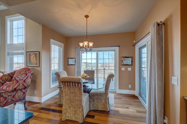 dining area with light wood-type flooring, baseboards, and a notable chandelier