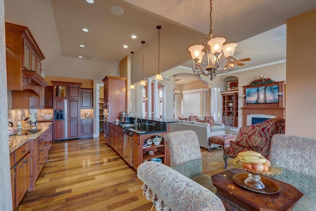 kitchen with ornate columns, arched walkways, a sink, stainless steel appliances, and open floor plan