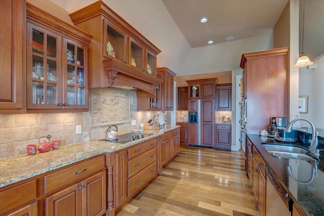 kitchen featuring stainless steel dishwasher, brown cabinetry, light stone countertops, and a sink