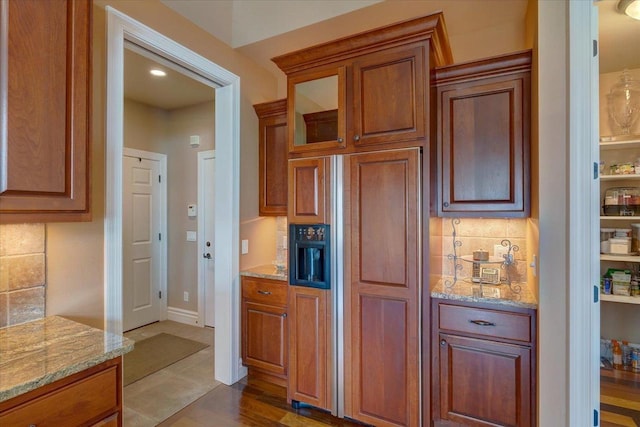 kitchen with dark wood-type flooring, light stone counters, backsplash, glass insert cabinets, and paneled built in refrigerator