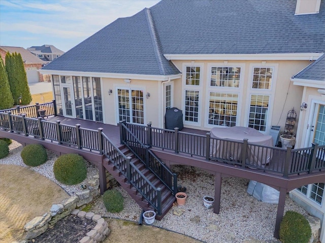 back of property with stucco siding, a deck, and a shingled roof