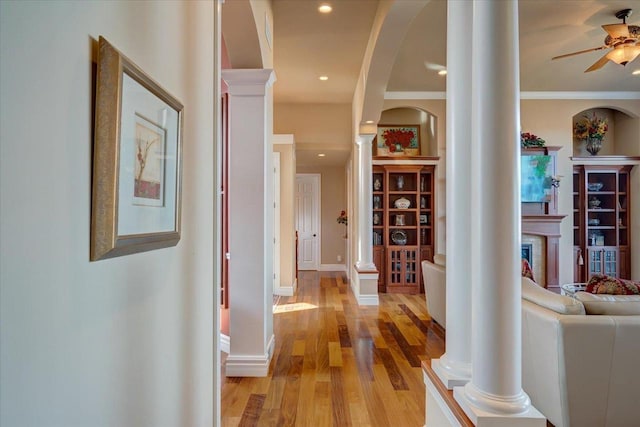 corridor with recessed lighting, arched walkways, light wood-style floors, baseboards, and ornate columns