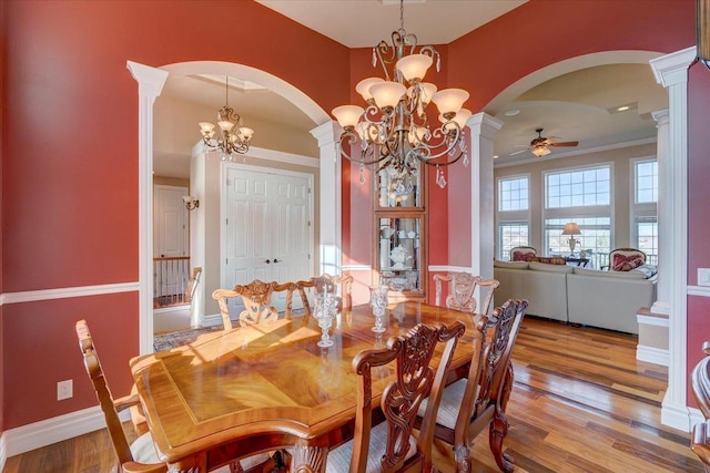 dining space with decorative columns, arched walkways, and wood finished floors