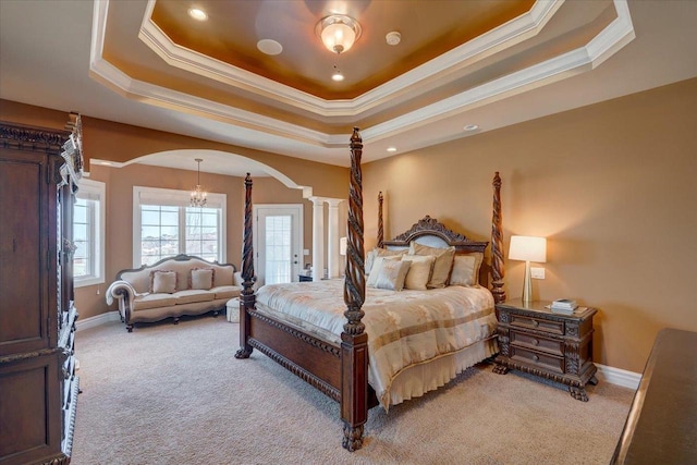 bedroom with a chandelier, decorative columns, light carpet, arched walkways, and a raised ceiling