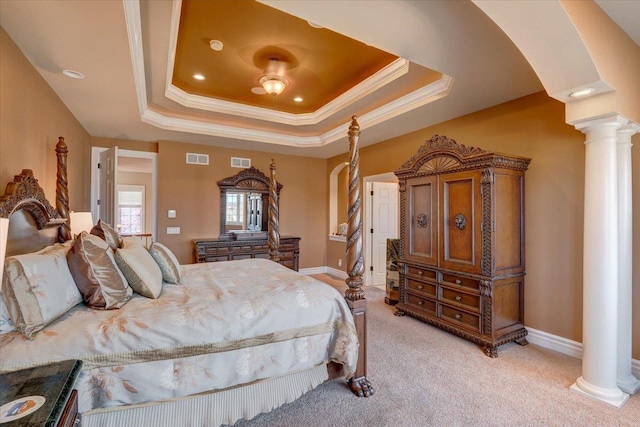 bedroom featuring arched walkways, visible vents, a tray ceiling, and decorative columns