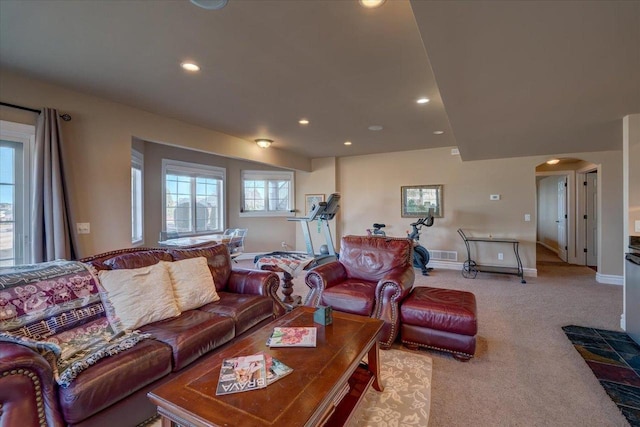 living room with baseboards, visible vents, recessed lighting, arched walkways, and light carpet