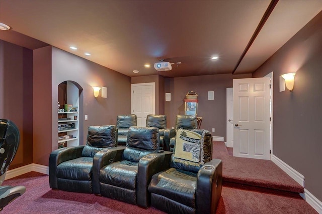 home theater room featuring arched walkways, recessed lighting, baseboards, and dark colored carpet