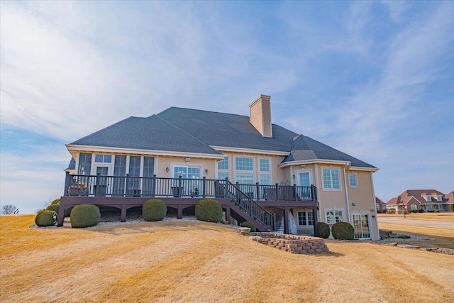 back of house featuring a wooden deck, a lawn, a chimney, and stairs