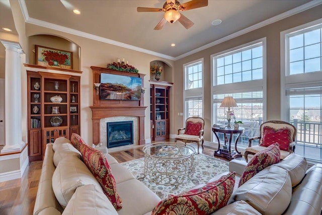 living room with ornamental molding, wood finished floors, ceiling fan, and decorative columns