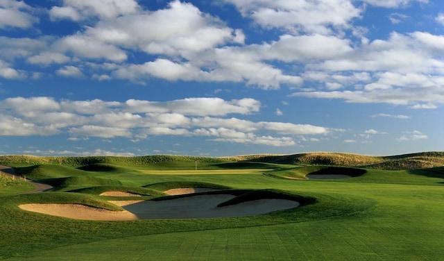 view of property's community featuring view of golf course and a lawn