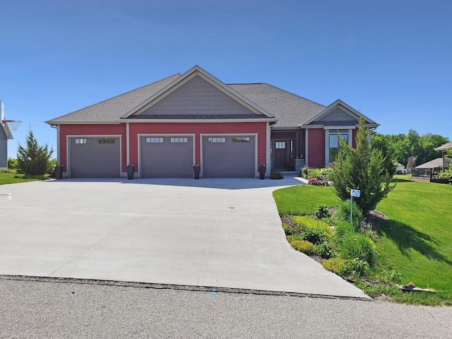 craftsman-style house featuring a front lawn, an attached garage, and driveway