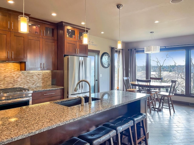 kitchen with decorative backsplash, appliances with stainless steel finishes, a kitchen breakfast bar, and a sink