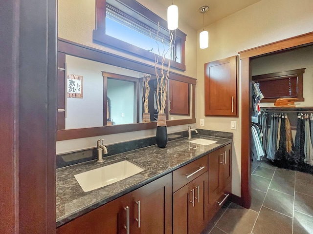 full bath featuring tile patterned flooring, double vanity, a walk in closet, and a sink