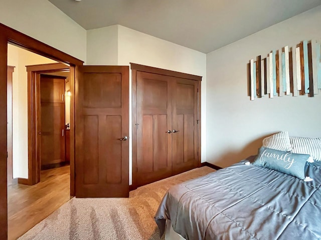 bedroom with light wood-style flooring, baseboards, and a closet