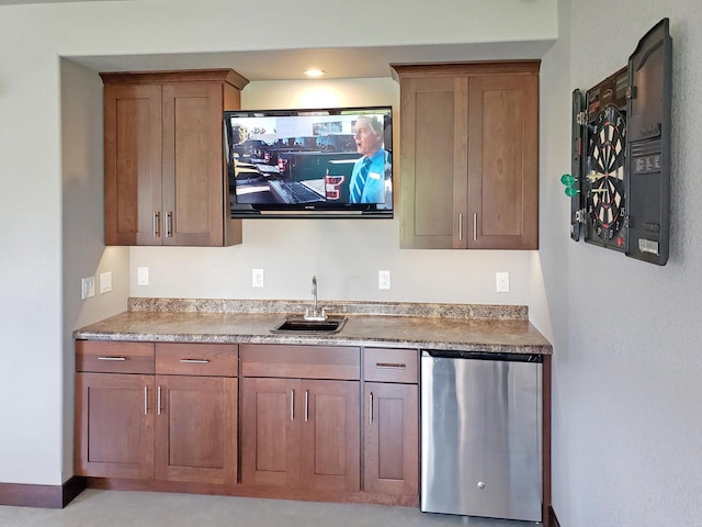 kitchen with a sink, brown cabinets, refrigerator, and light countertops