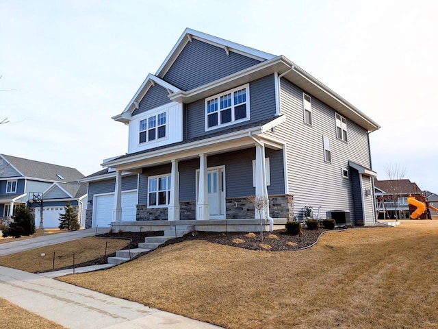 craftsman inspired home featuring an attached garage, a front lawn, covered porch, stone siding, and driveway