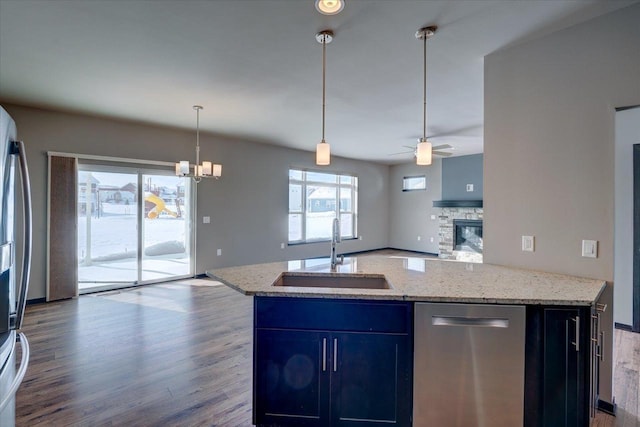 kitchen with ceiling fan with notable chandelier, a sink, wood finished floors, open floor plan, and stainless steel appliances