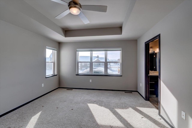 unfurnished room featuring a tray ceiling, plenty of natural light, and baseboards