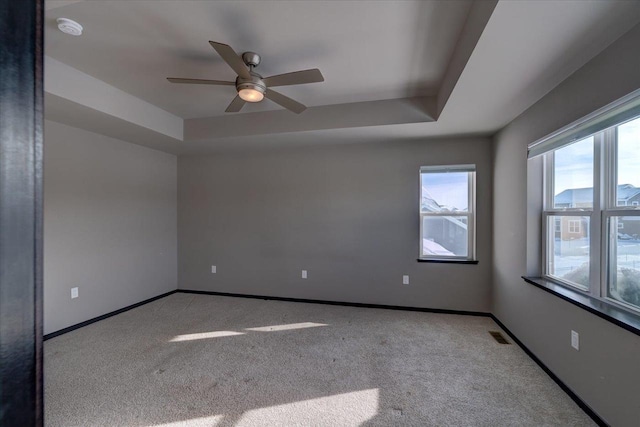 unfurnished room featuring baseboards, a raised ceiling, visible vents, and ceiling fan