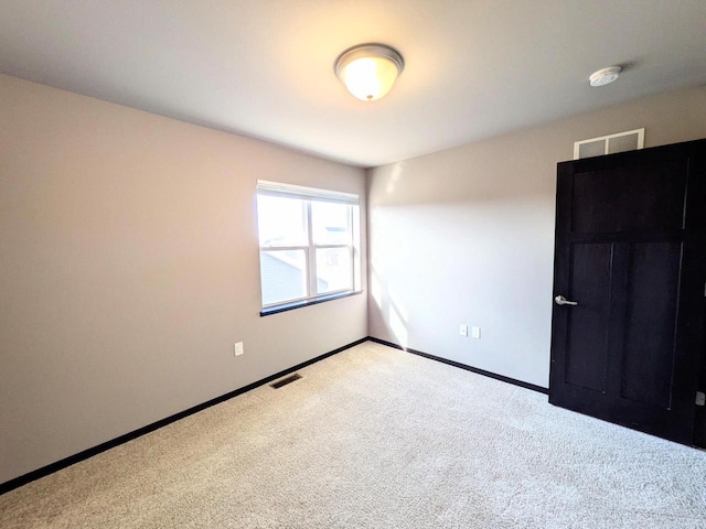 unfurnished room with carpet, visible vents, and baseboards