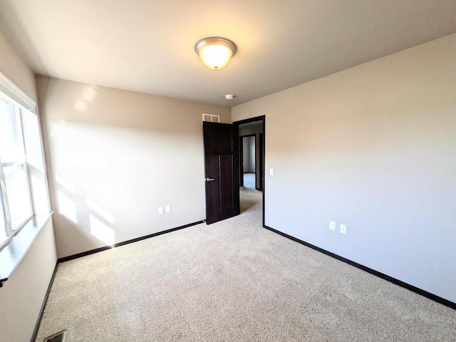 spare room with visible vents, baseboards, and light carpet