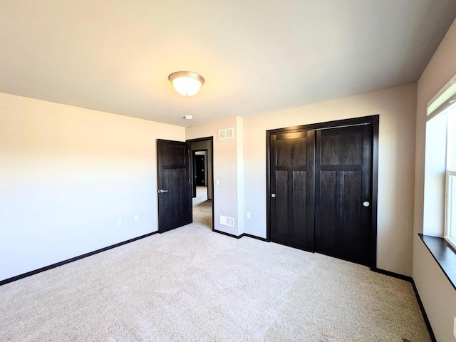 unfurnished bedroom featuring visible vents, baseboards, light colored carpet, and a closet