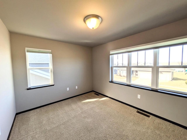 carpeted spare room featuring baseboards and visible vents