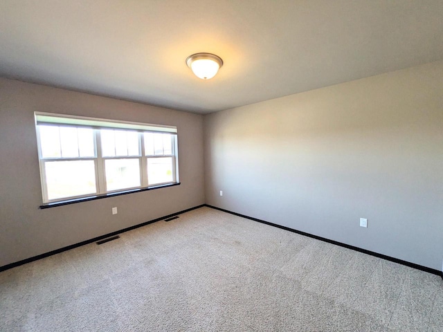 empty room featuring visible vents, carpet flooring, and baseboards