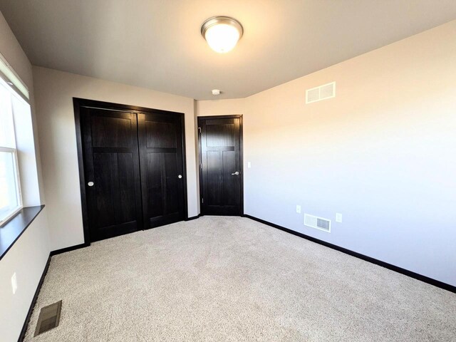 unfurnished bedroom with visible vents, baseboards, carpet, and a closet