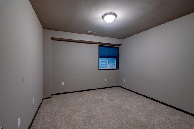 carpeted spare room featuring baseboards and visible vents