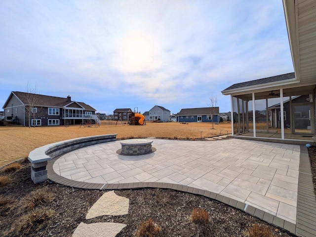 view of patio featuring a playground, a ceiling fan, and an outdoor fire pit