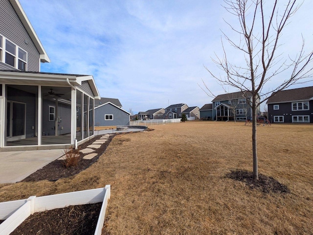 view of yard featuring a ceiling fan, a patio area, a residential view, and a sunroom