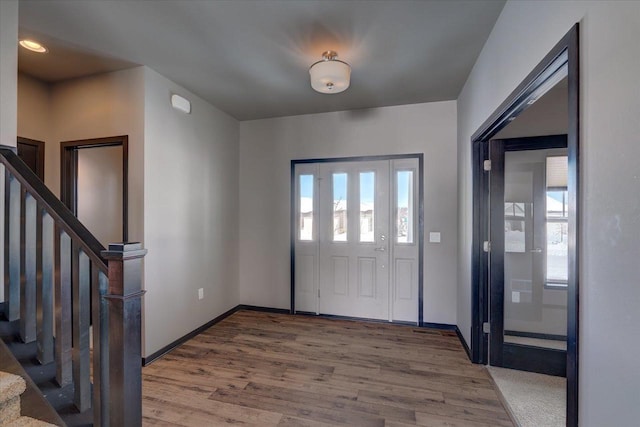 entrance foyer with stairway, wood finished floors, and baseboards