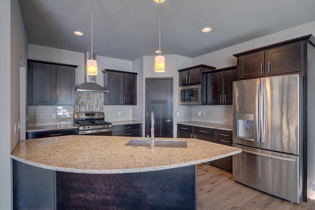 kitchen with light stone counters, a sink, stainless steel appliances, dark brown cabinetry, and wall chimney exhaust hood