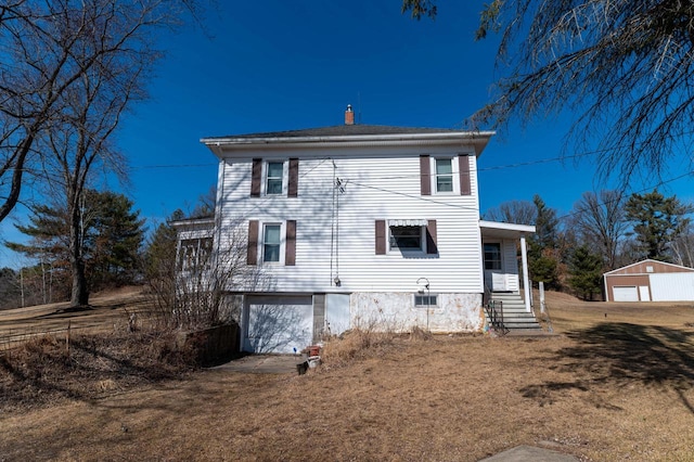 rear view of house featuring a garage, a lawn, and an outdoor structure