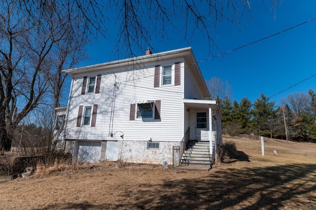 rear view of house featuring a yard, a chimney, and a garage