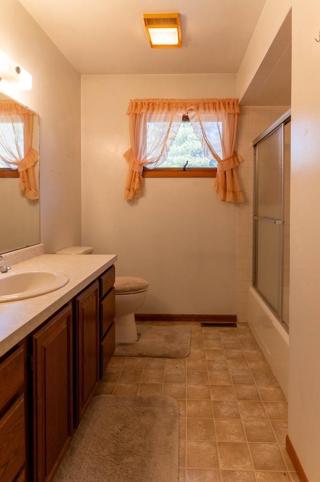 full bathroom with vanity, baseboards, visible vents, shower / bath combination with glass door, and toilet