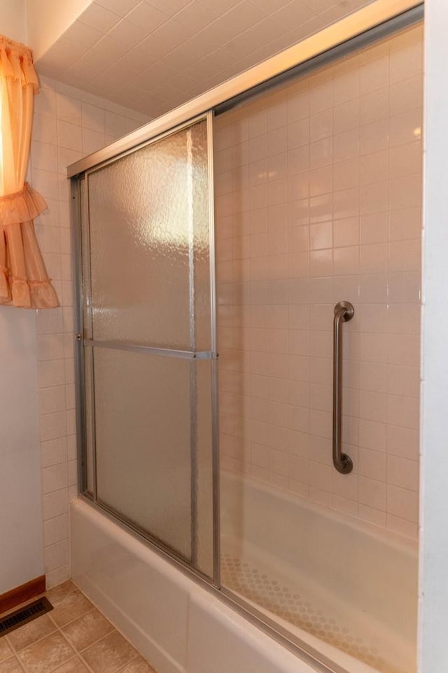 bathroom with tile patterned floors, visible vents, and bath / shower combo with glass door