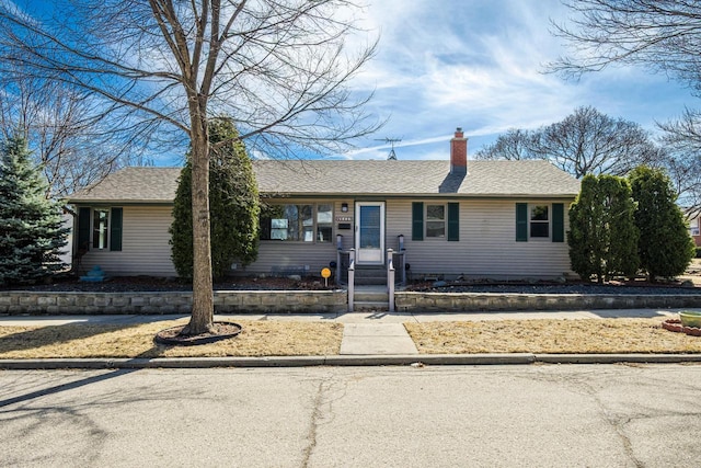 ranch-style house with roof with shingles and a chimney