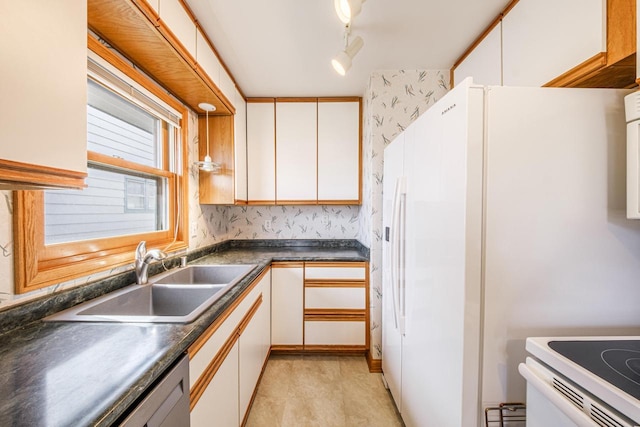 kitchen with a sink, dark countertops, white appliances, white cabinets, and wallpapered walls