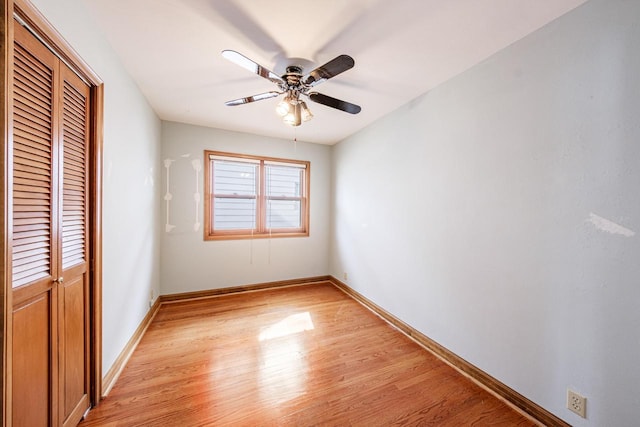 unfurnished bedroom featuring baseboards, light wood-type flooring, a closet, and ceiling fan