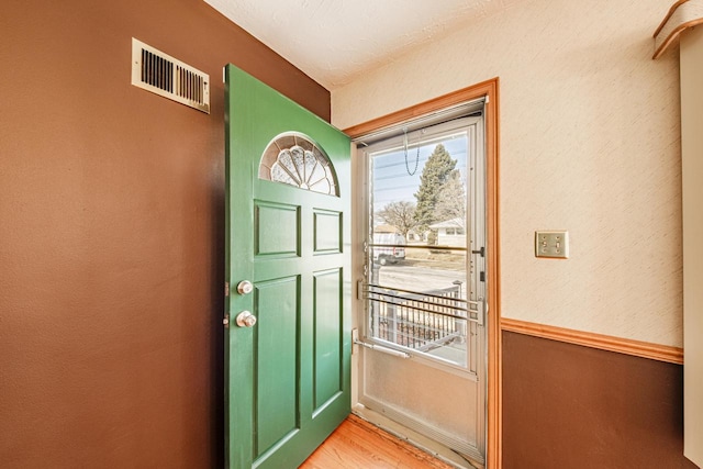 doorway with a textured wall, visible vents, plenty of natural light, and light wood finished floors