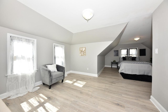 bedroom with baseboards, lofted ceiling, and light wood-style floors